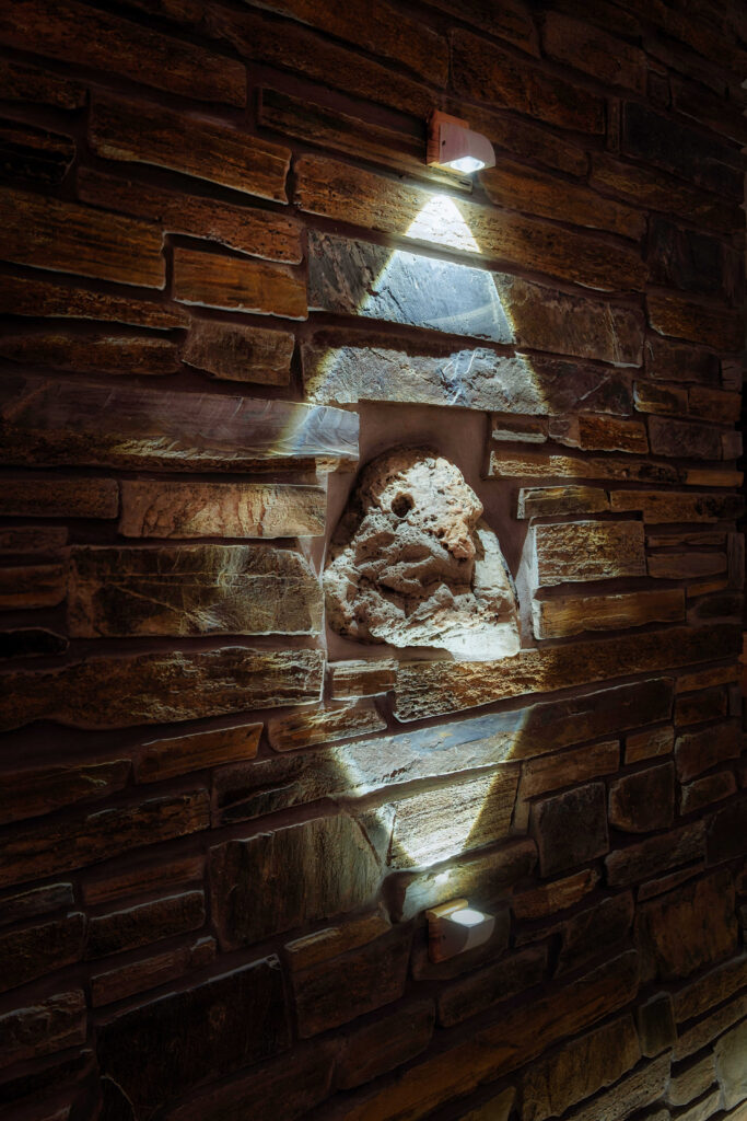 Detail of a stone wall with artistic niche lighting, adding ambiance to a retreat's interior space.