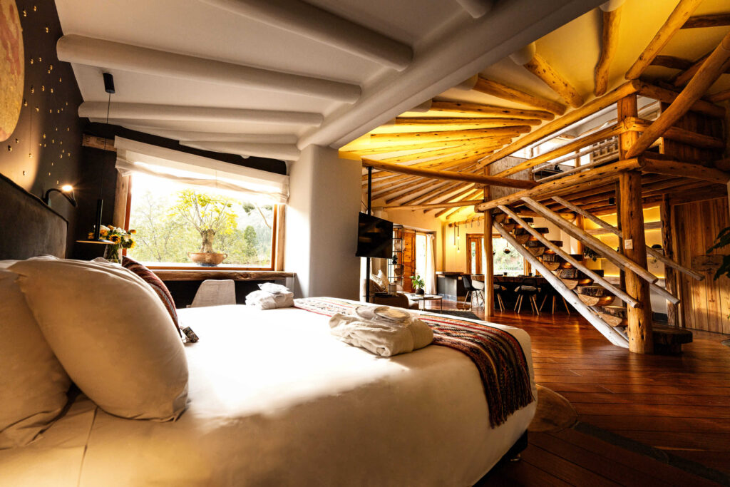 Inviting and bright bedroom with a view, featuring warm wooden architecture and a cozy, modern design in a luxury ayahuasca retreat setting