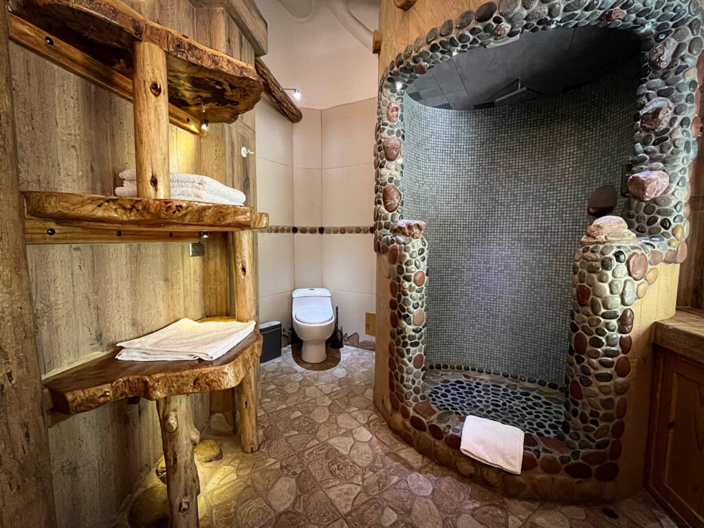 Experience rustic elegance with this uniquely crafted shower enclave, featuring natural wood and stone details, in the luxury surroundings of a Sacred Valley ayahuasca retreat in Peru