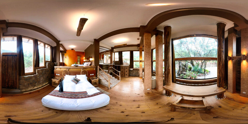 A panoramic view of a spacious, circular room with natural wood architecture and large windows inviting ample light and serene views