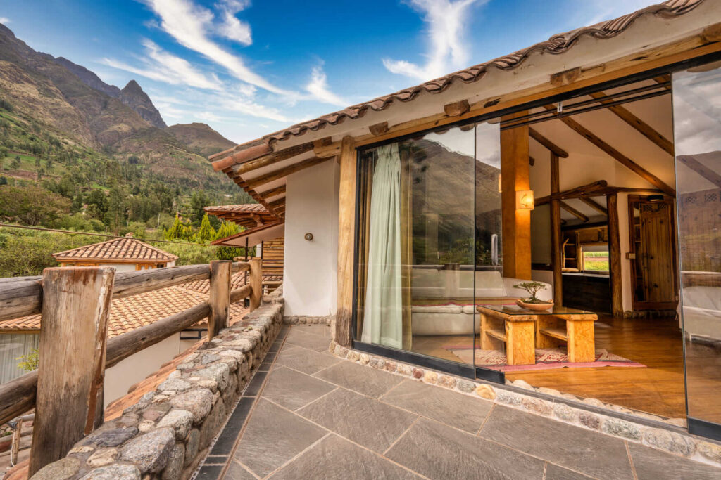 The Sunbeam Suite Terrace at Ayahuasca Lux offers an inviting outdoor space with rustic stone and wood elements, seamlessly integrating with the serene mountain landscape, perfect for relaxation and reflection.