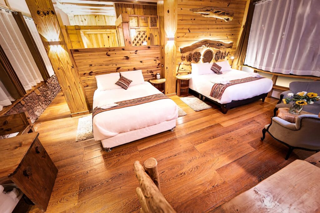 A warmly lit, wood-crafted twin bedroom with plush beds and rustic decor, offering a welcoming retreat ambiance.